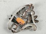 a silver brooch with a carrot in it on a white surface