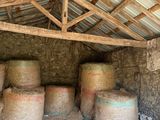 many stacks of hay in a building with a roof