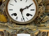 a gold clock with a white face and a bird on it