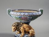 une statue représentant un lion assis sur un bol