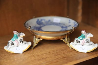 deux figurines miniatures posées sur une étagère à côté d'un bol