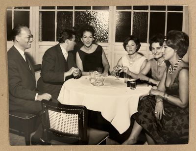 Plusieurs personnes sont assises autour d'une table, un verre de vin à la main.