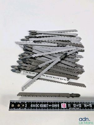 une règle posée à côté d'une pile de scies