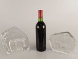 a bottle of wine next to a glass block and a bottle of wine