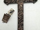 une vieille croix en métal, avec un briquet à côté, posée sur une surface blanche