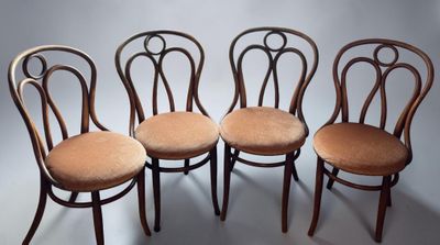 four chairs with curved backs are lined up against a white background
