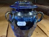 a blue glass jar with a tag on it sitting on a wooden table