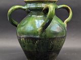 a green vase with two handles sitting on a table