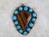 a close up of a pendant with a tiger ' s eye and turquoise beads