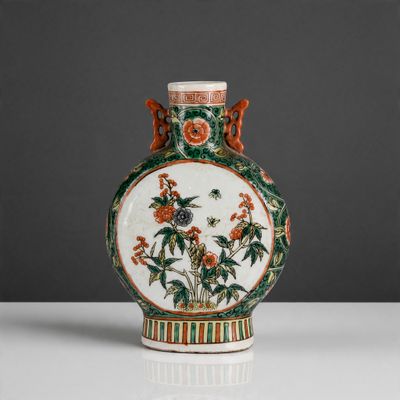 an orange and green vase with birds and flowers on it