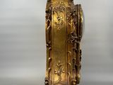 a gold clock on a stand with a bird on top