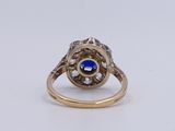 a close up of a gold ring with a blue stone surrounded by diamonds