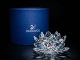 La fleur de cristal est posée sur la table, à côté d'une boîte bleue.