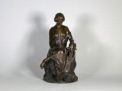 statue en bronze représentant une femme assise sur un rocher, tenant un panier de fleurs