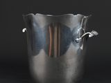 a large metal pot with a handle on a black background