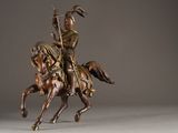 statue of a man riding a horse with a spear on his back