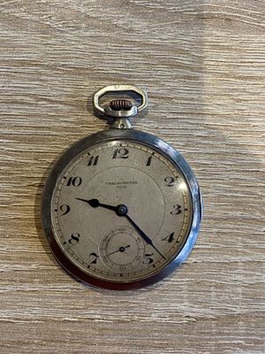une montre de poche en argent posée sur une table en bois