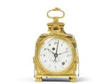 une horloge en or posée sur une surface blanche