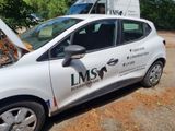 a small white car parked in front of a moving truck