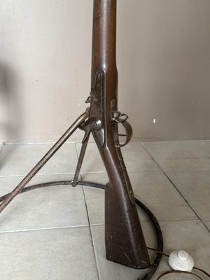 a wooden rifle on the floor next to a lamp