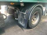 a green semi truck with a flat tire parked in a parking lot