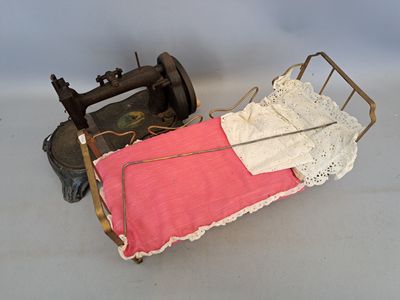 un petit lit de poupée avec une couverture rose et une machine à coudre