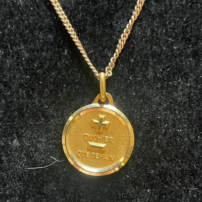 a close up of a gold coin on a chain on a black surface