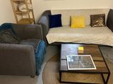 un salon avec un canapé, un fauteuil, une table basse et une fenêtre