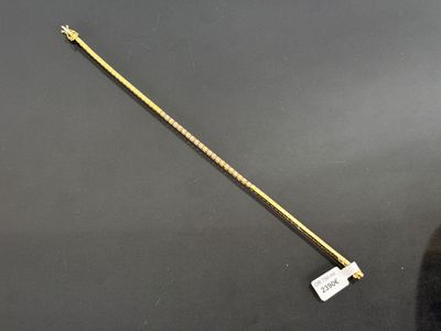 a gold plated stick with a long handle on a black surface