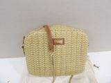 beige straw bag with chain strap and name tag on it