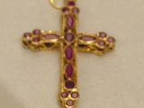 a close up of a gold cross with pink stones on it