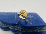 un gros plan d'une bague en or sur laquelle est sertie une pierre bleue