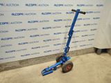 a blue hand truck that is parked in front of a wall