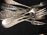 a lot of silver spoons and forks on a black table