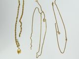 three gold necklaces and a necklace with a cross on a white background