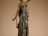 bronze statue of a woman holding a basket of flowers on a pedestal