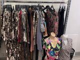 a woman standing in front of a rack of clothes in a clothing store