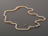 a close up of a necklace with pearls on a table