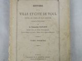 un vieux livre posé sur une table, à côté d'une étiquette bleue