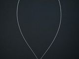 a white gold necklace with a white diamond pendant on a black background