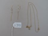 trois colliers en or et une paire de boucles d'oreilles avec une étiquette de prix