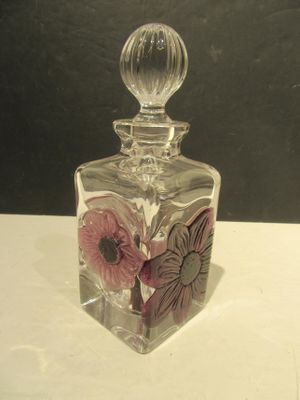 a clear glass bottle with a flower design on it
