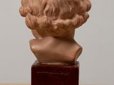 bust of a young boy with curly hair on a wooden base