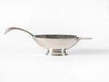 a silver bowl with a spoon on top of it on a white surface