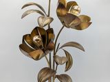 gold metal flowers on a black wooden base with a white background