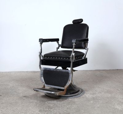 Fauteuil de barbier en cuir noir et structure en inox.