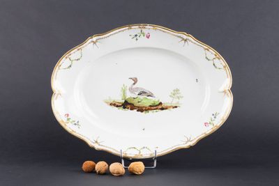 un gros plan sur une assiette sur laquelle sont disposés un oiseau et des noix