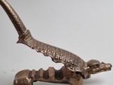brass figurine of a lizard with a long neck and a long tail