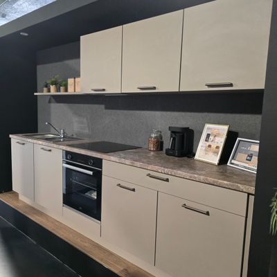a kitchen with a sink, stove, oven, and picture frame on the wall