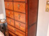 a tall wooden chest of drawers in the corner of a bedroom